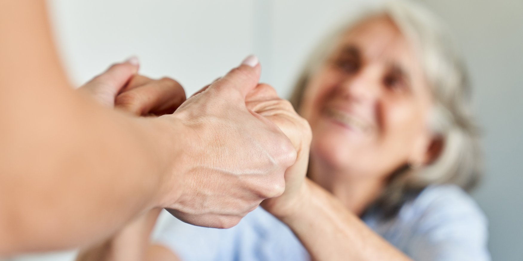 Caregiver gently holding the hands of an older adult, offering comfort and reassurance.